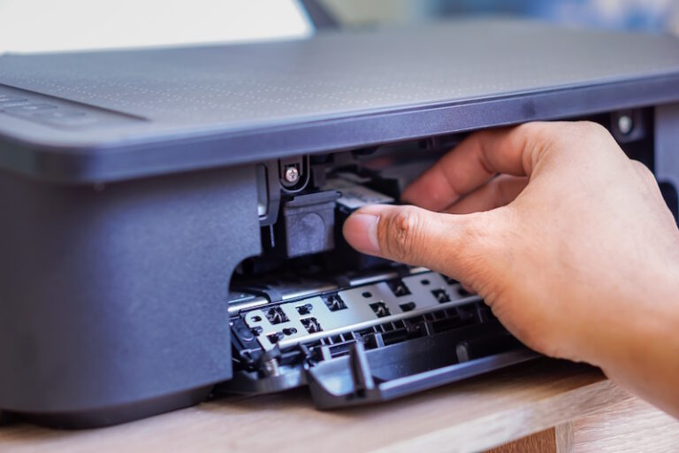 person is installing black ink cartridge into printer 768x512